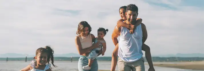 Chiropractic Cape Coral FL Family Chiropractic A family of 5 walking along a beachside. The wind is blowing and they are all smiling